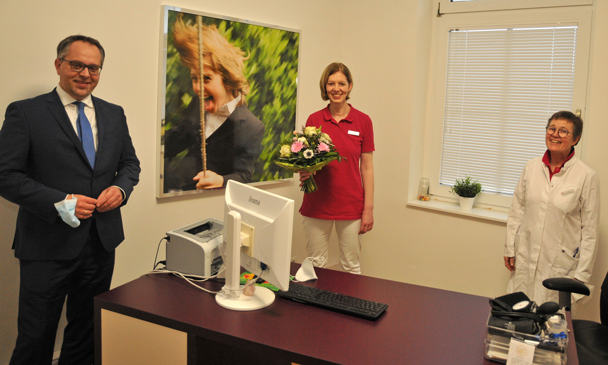 Der Bürgermeister (von links) begrüßt Dr. Wülfing (mitte) mit einem Straß Blumen für die Übernahme der Praxis von Dr. Reichenberger (rechts)