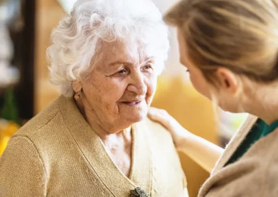 Eine alte Dame wird sorgsam von einer jungen Pflegerin betreut.
