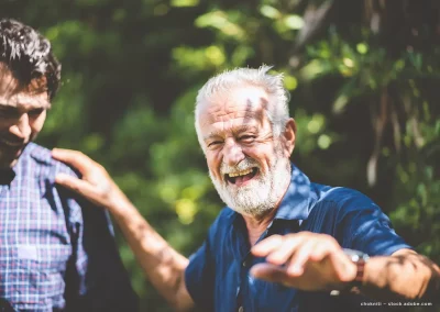 Ein älterer Herr wird lachend in einer lockeren Atmosphäre dargestellt.